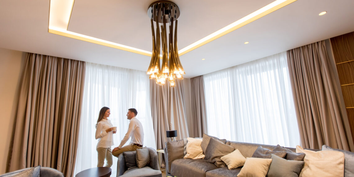 Young couple relaxing and talking with coffee cups in the luxurious room of contemporary apartment