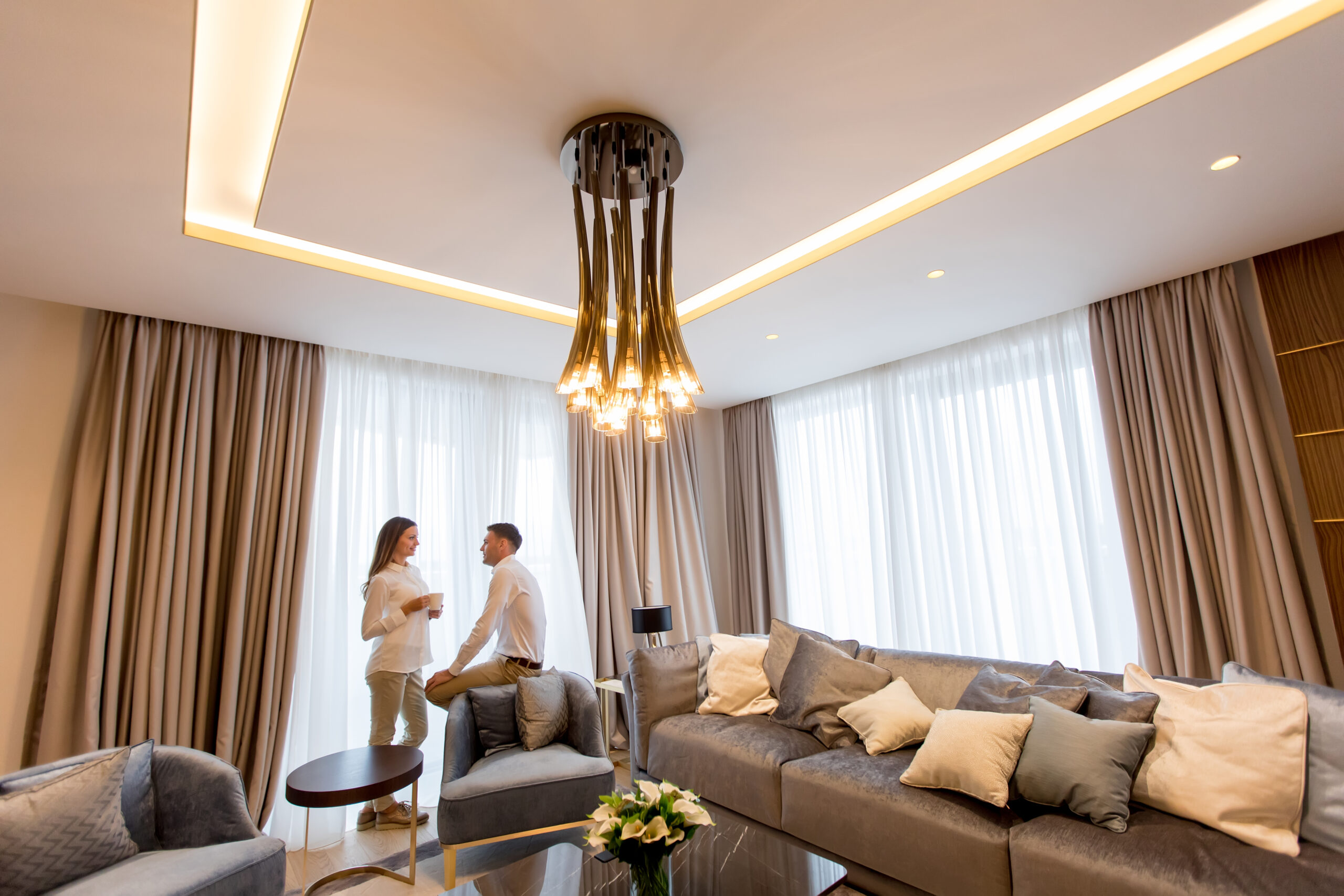 Young couple relaxing and talking with coffee cups in the luxurious room of contemporary apartment